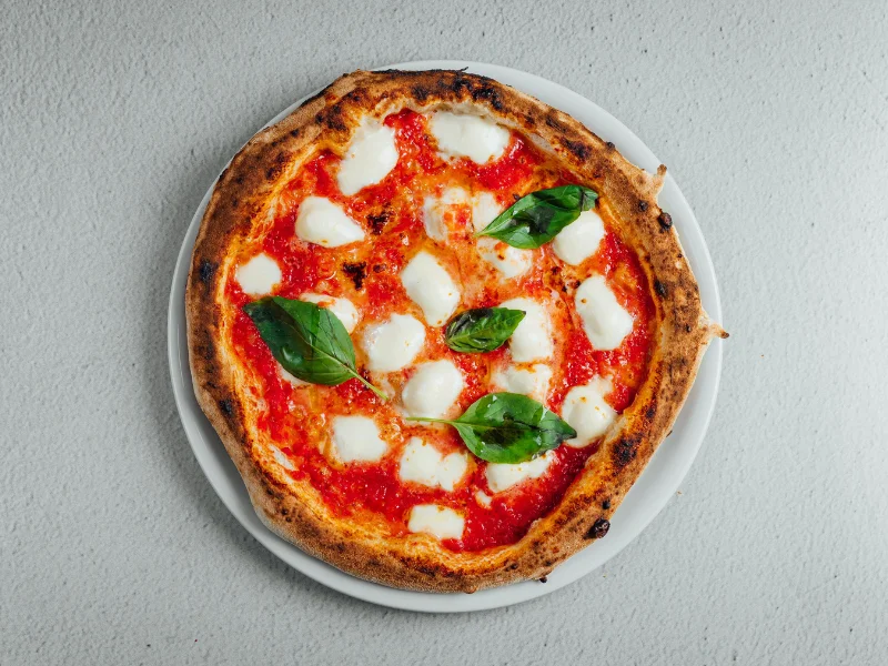 The toppings on a Pizza Margherita resemble the Italian flag. Red tomato sauce, white Mozzarella cheese, and green basil.